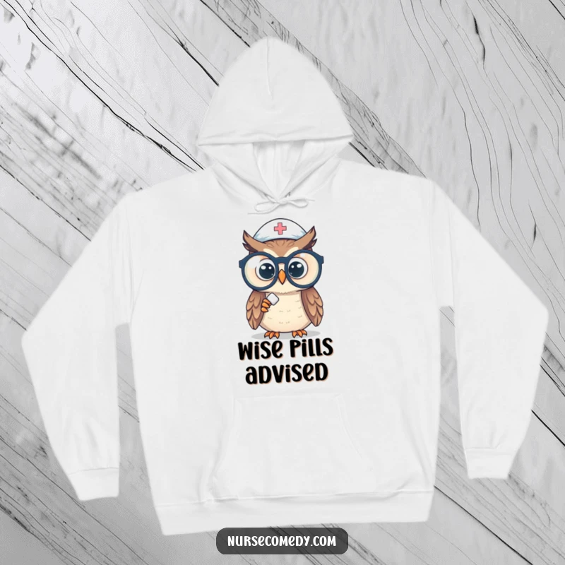 Funny owl nurse hoodie depicting a curious owl wearing large spectacles, focusing intently on a small pill, offering warmth and wit.